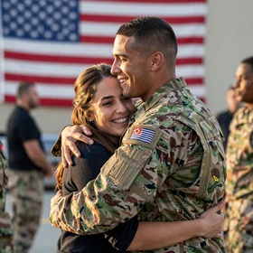 Woman greeting a man in uniform at an airport reunion, a warm uniform dating homecoming moment